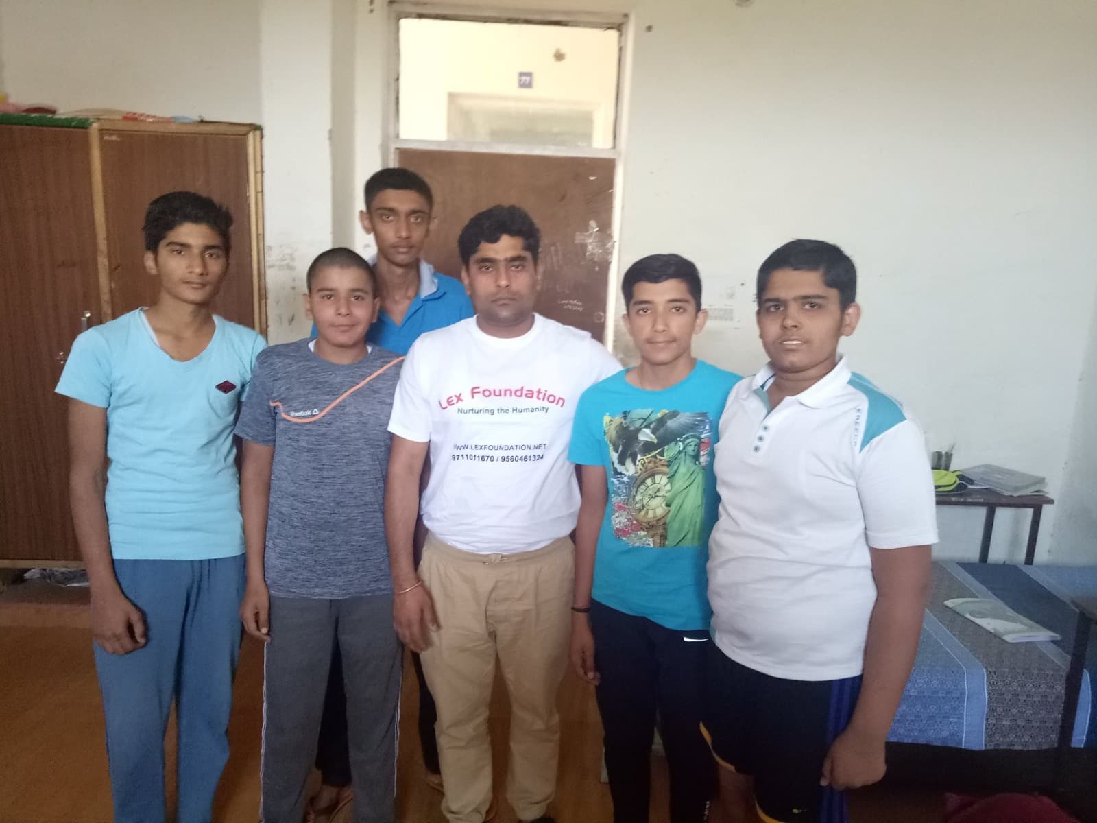 A Lex Foundation mentor posing with five students in a residential room.