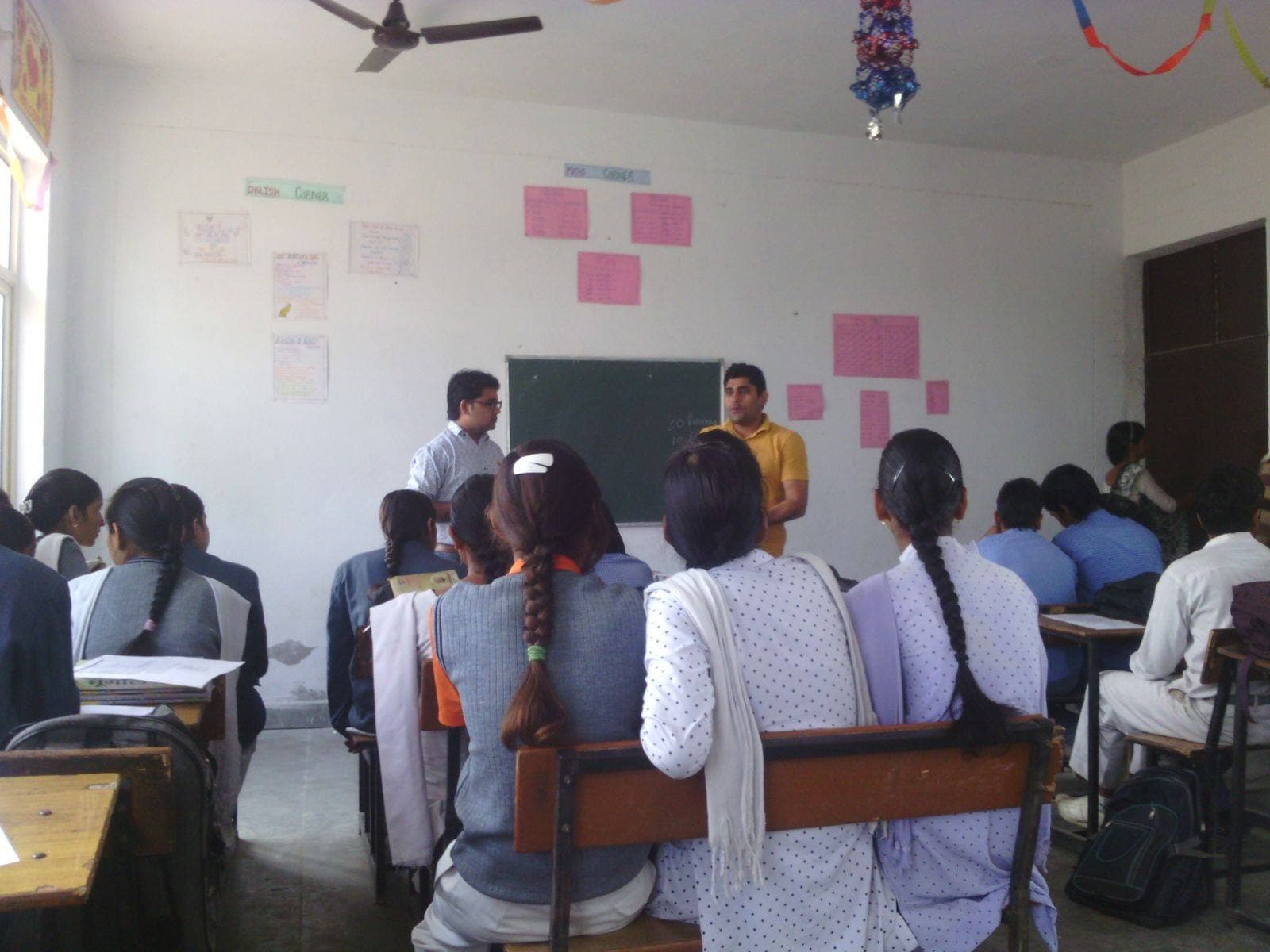 Two facilitators leading a classroom discussion with students seated at their desks.